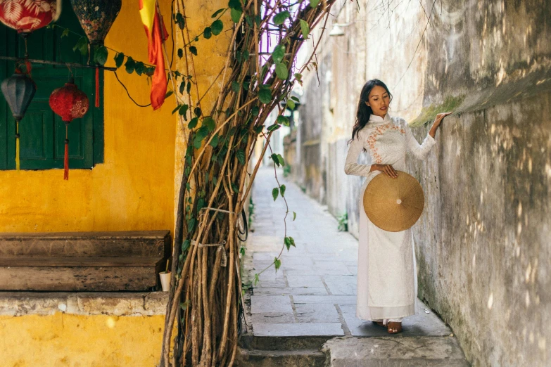 a woman in a white dress is holding a fan, inspired by Ruth Jên, pexels contest winner, happening, clothed in ancient street wear, ao dai, holding a shield, wearing straw hat