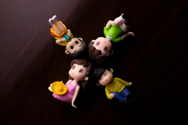 a group of small figurines sitting on top of a wooden table, a picture, by Fei Danxu, pexels contest winner, kids toy, high-angle, casual pose, pvc figurine