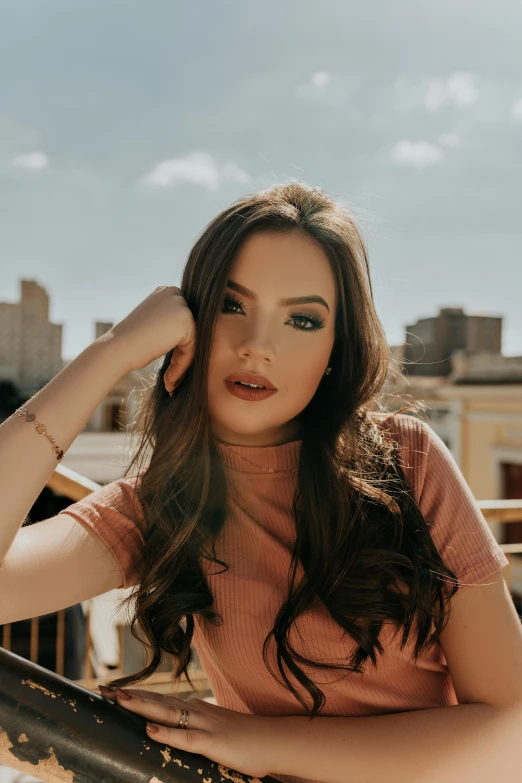 a woman posing for a picture on a balcony, an album cover, by Robbie Trevino, trending on pexels, long brunette hair, anna nikonova aka newmilky, hailee steinfeld, city view