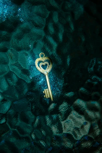 a close up of a gold key on a blue background, an album cover, by Elsa Bleda, trending on unsplash, symbolism, 3 d ornate carved water heart, glass and gold and jade, or perhaps a fairy tale, mobile wallpaper