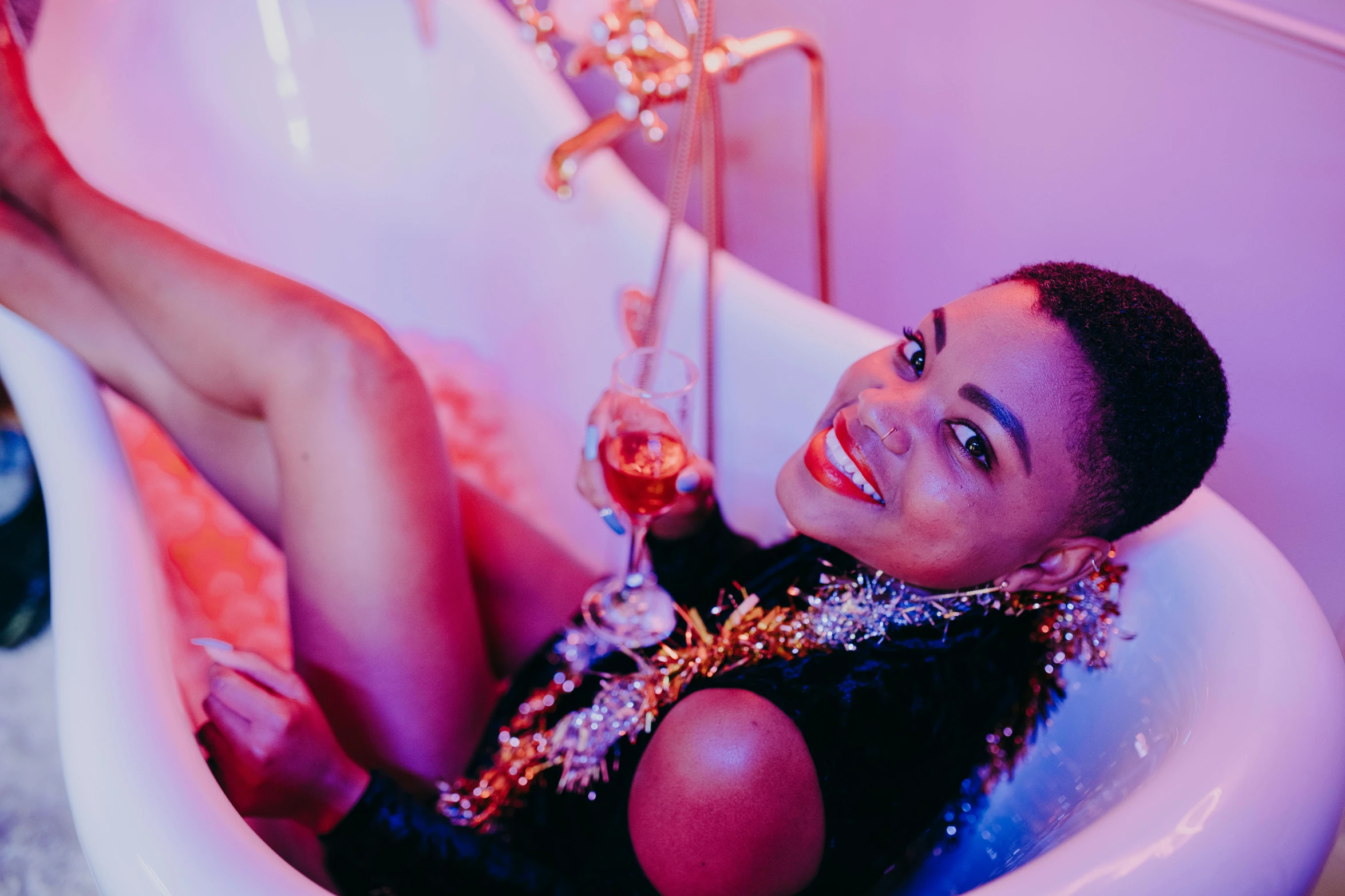 a woman that is laying down in a bathtub, trending on pexels, process art, chillin at the club together, aida muluneh, champagne, relaxing and smiling at camera