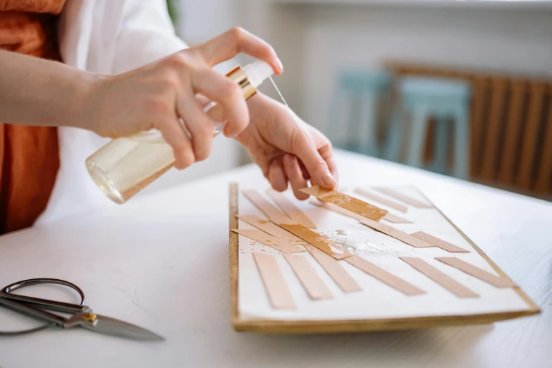 a close up of a person with scissors on a table, by Julia Pishtar, maple syrup sea, ivory and copper, assembly instructions, unsheathing her katana