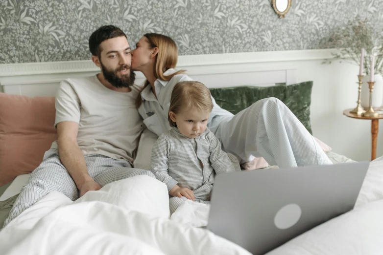 a man and woman sitting on a bed with a baby and a laptop, pexels, figuration libre, avatar image, hugging, grey, high resolution image