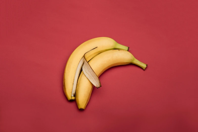 a couple of bananas sitting on top of a red surface, taken with sony alpha 9, a blond, detailed product image, piled around