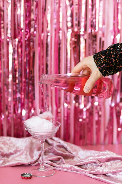 a close up of a person pouring something into a glass, by Julia Pishtar, pink background, party, glittering ice, romantic themed