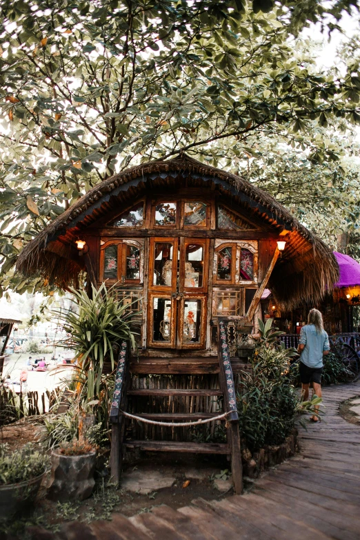 a couple of people that are standing in front of a building, floral jungle treehouse, bamboo huts, pub, hippie pad