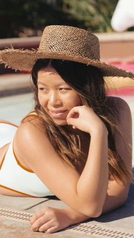 a beautiful woman laying on top of a swimming pool, by Robbie Trevino, trending on pexels, wearing straw hat, asian descent, portrait of zendaya, digital image