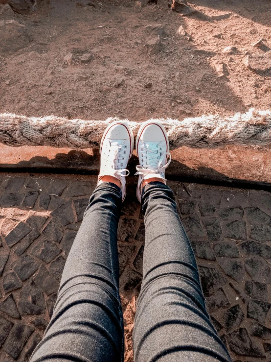 a person sitting on top of a rock next to a rope, a picture, inspired by Elsa Bleda, trending on pexels, blue jeans and grey sneakers, in an abandoned theme park, detailed shot legs-up, 🤬 🤮 💕 🎀