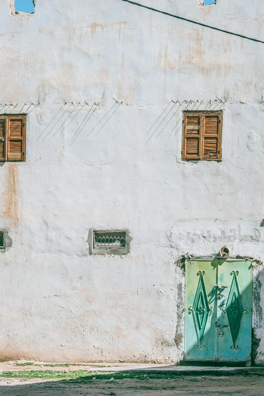 a motorcycle parked in front of a white building, a photo, inspired by Riad Beyrouti, trending on unsplash, graffiti, muted green, view of villages, little windows, full frame image