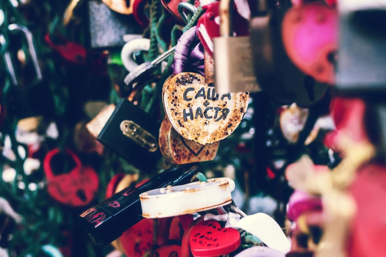 a close up of a bunch of locks on a fence, by Julia Pishtar, trending on pexels, graffiti, several hearts, close up shot of an amulet, 💋 💄 👠 👗, a labeled