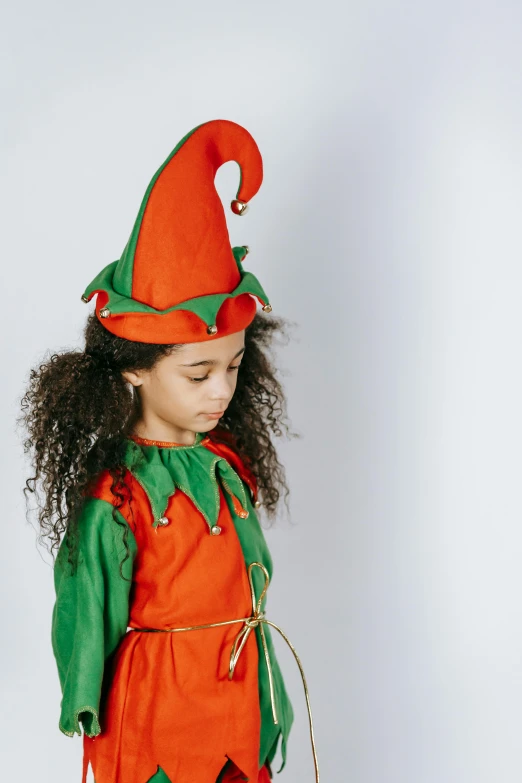 a little girl dressed in an orange and green costume, female elf, full product shot, red cap, multi colour