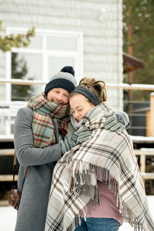 a man and woman wrapped in a blanket in the snow, tartan scarf, in style of heikala, grey, small
