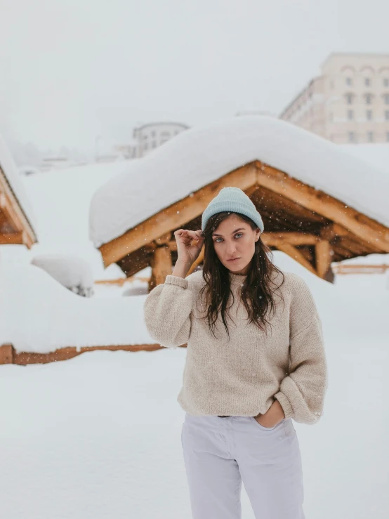 a woman standing in the snow wearing a hat, bluish and cream tones, photoshoot for skincare brand, on rooftop, chamonix