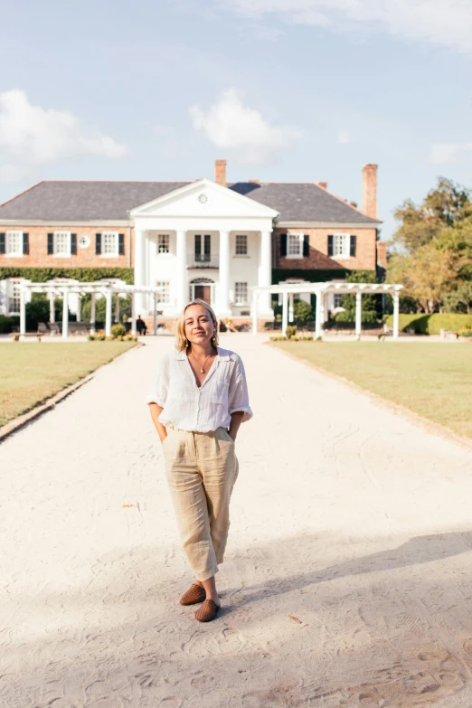 a woman standing in front of a large house, a portrait, inspired by Elizabeth Charleston, trending on unsplash, standing in the savannah, slightly tanned, colonial, official screenshot