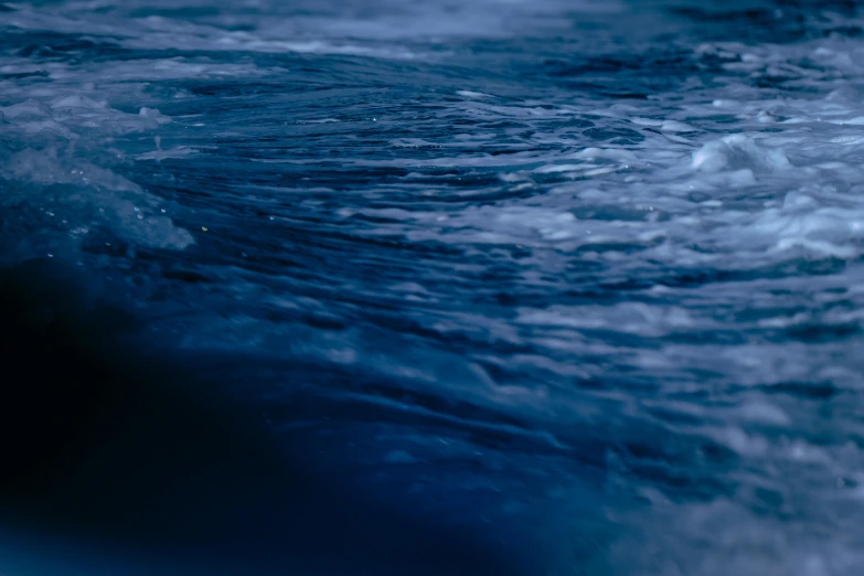 a man riding a wave on top of a surfboard, an album cover, by Elsa Bleda, unsplash, hurufiyya, midnight blue, extremely detailed water texture, ignant, a close-up