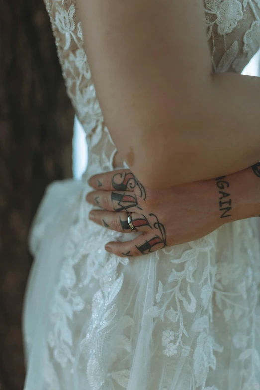 a woman with a tattoo on her arm, inspired by Elsa Bleda, trending on unsplash, wearing a wedding dress, gnarled fingers, colored photo, 👅 👅