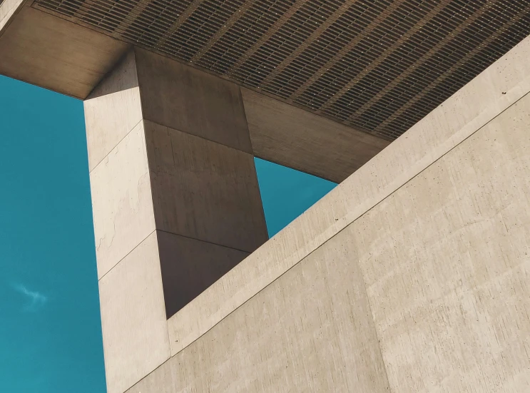 a clock that is on the side of a building, an album cover, inspired by Ned M. Seidler, unsplash contest winner, brutalism, brown and cyan blue color scheme, shooting angle from below, concrete, high-angle