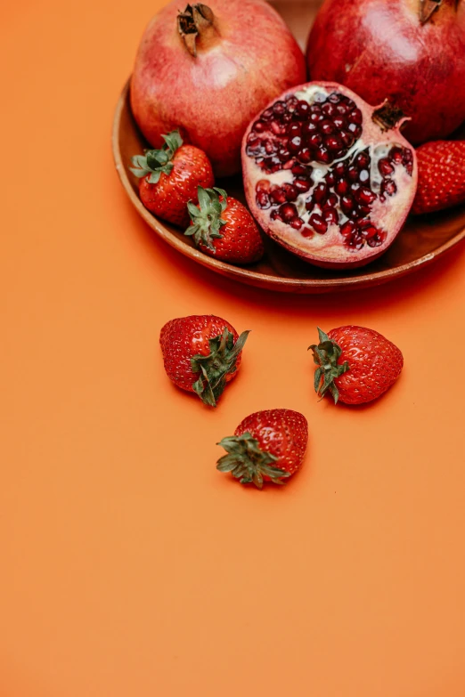 a plate of strawberries and pomegranates on an orange background, pexels contest winner, complementary color, opening shot, multiple stories, on a gray background