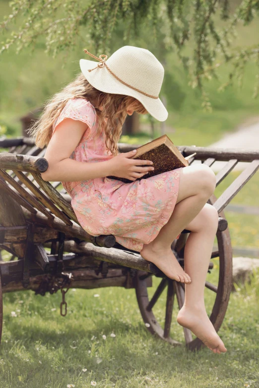 a little girl sitting on a bench reading a book, inspired by Elsa Beskow, renaissance, wearing straw hat, trending photo, barefoot, teen girl