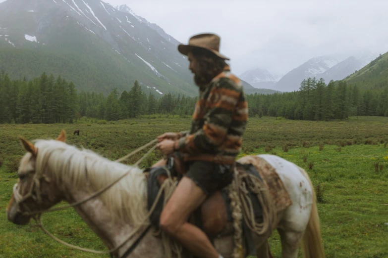 a man riding on the back of a white horse, an album cover, inspired by Konstantin Vasilyev, unsplash contest winner, still from nature documentary, wearing dirty travelling clothes, mountain scape. film still, nat geo