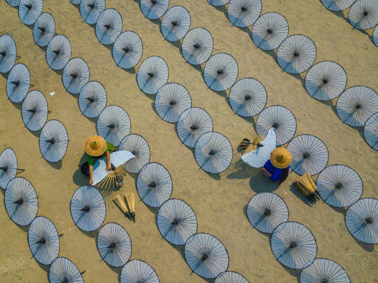 a group of people standing next to each other with umbrellas, inspired by Ai Weiwei, unsplash contest winner, aerial view, myanmar, thatched roofs, two hovering twin nuns