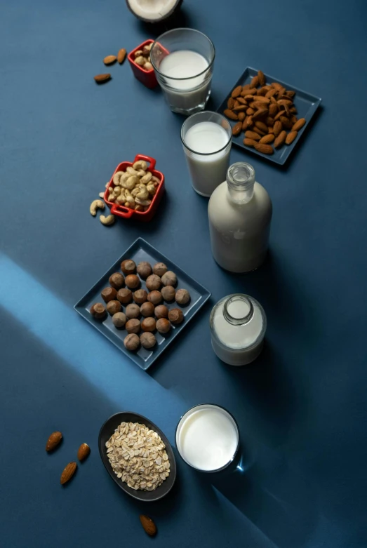 a table topped with bowls of nuts and milk, a still life, unsplash, dau-al-set, blue, product view, malt, angled shot