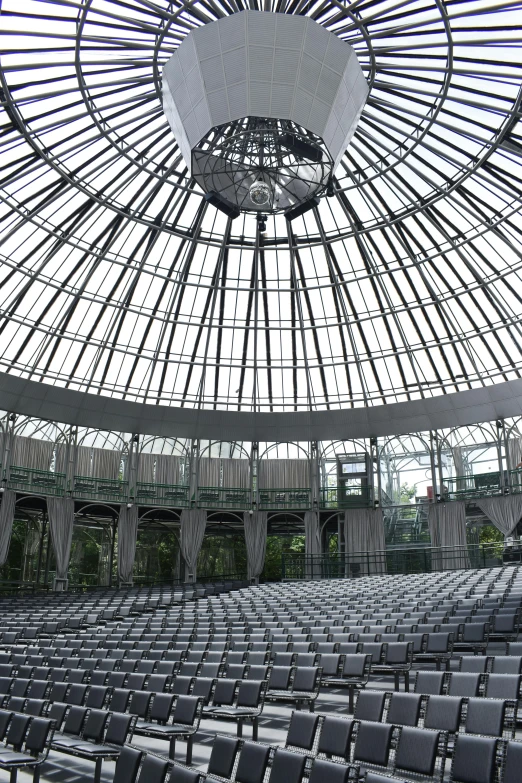 a large room filled with lots of empty chairs, inspired by Buckminster Fuller, light and space, exterior botanical garden, wrought iron architecture, glass dome, stage