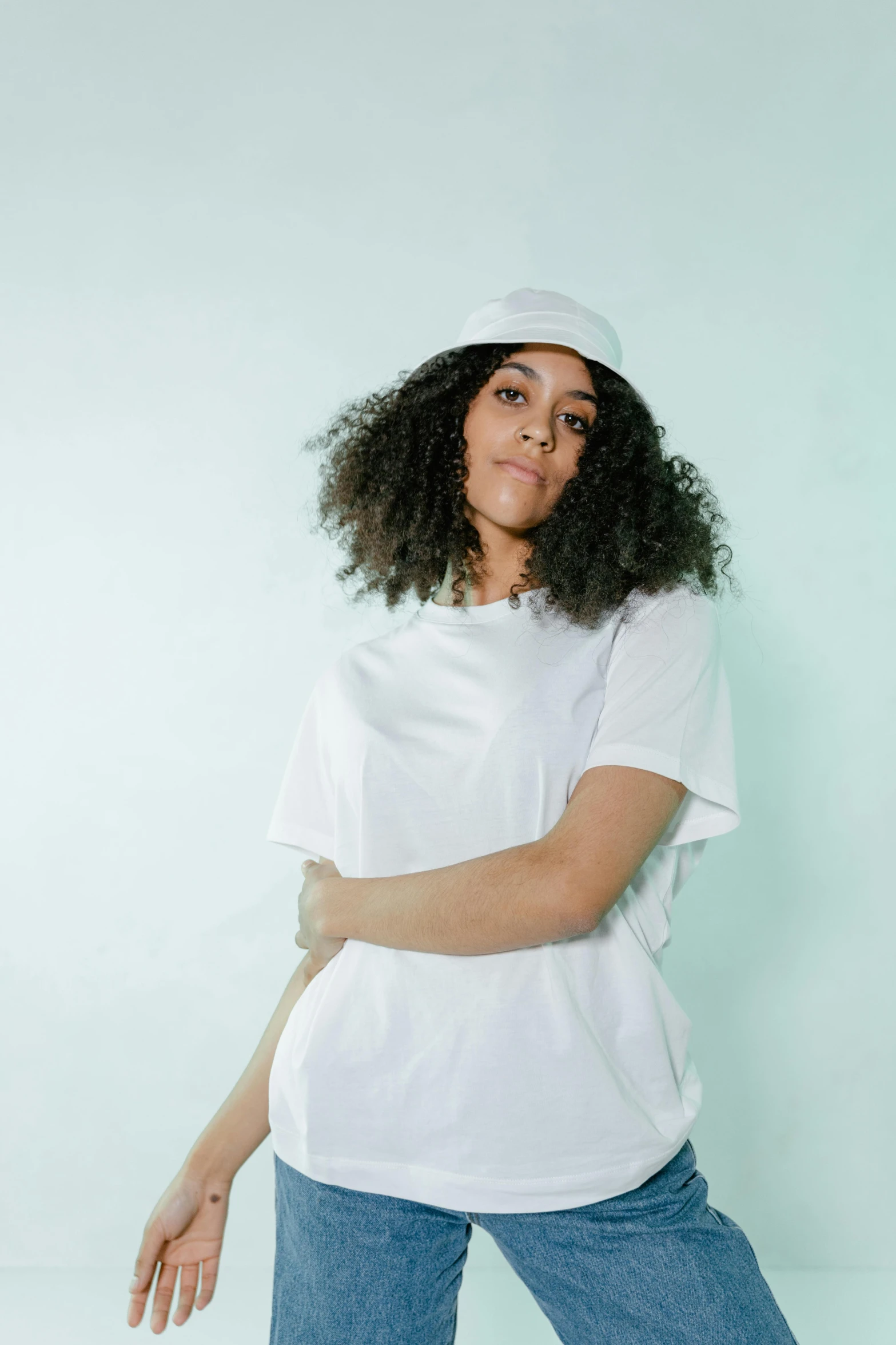 a woman wearing a white t - shirt and jeans, an album cover, trending on pexels, curls and curves, baggy clothing and hat, portrait mode photo, white uniform