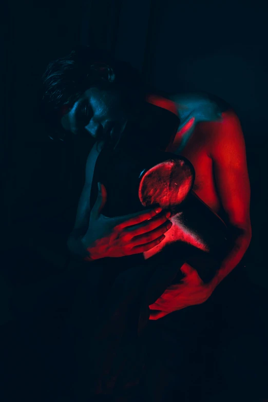 a man standing in the dark with his hand on his chest, an album cover, inspired by Elsa Bleda, pexels contest winner, art photography, red veins, a woman holding an orb, muscular and exhausted woman, abstract human body