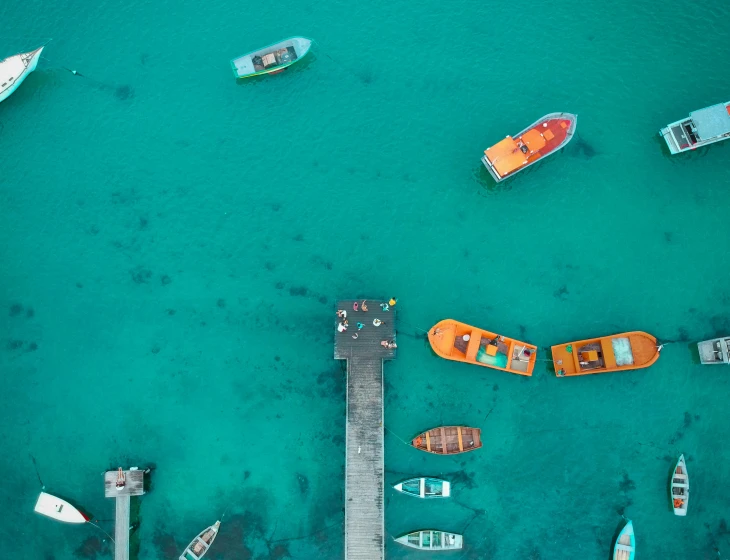 a group of boats floating on top of a body of water, a screenshot, by Lee Loughridge, pexels contest winner, turqouise, near a jetty, flatlay, cyan and orange