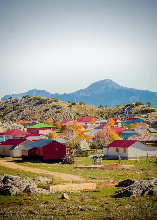 a small village with a mountain in the background, by Lee Loughridge, dau-al-set, vivid - colors, in chuquicamata, orange roof, overview