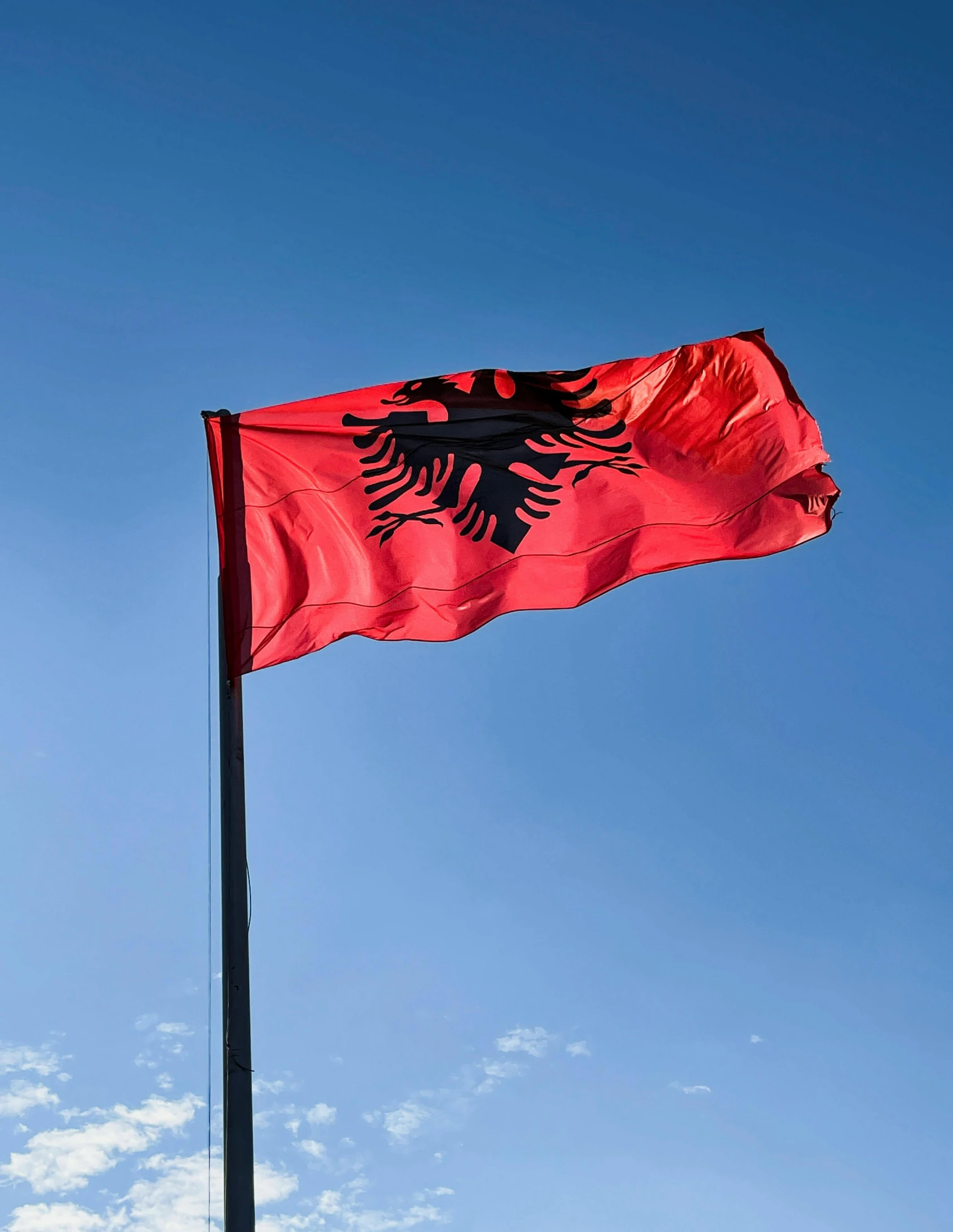 a red and black flag flying in the sky, agharta, profile image, multiple stories, olympics