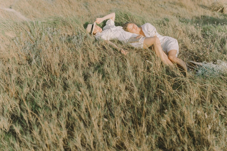 a couple of people laying on top of a grass covered field, unsplash, romanticism, valentin serov style, high resolution film still, ignant, prairie