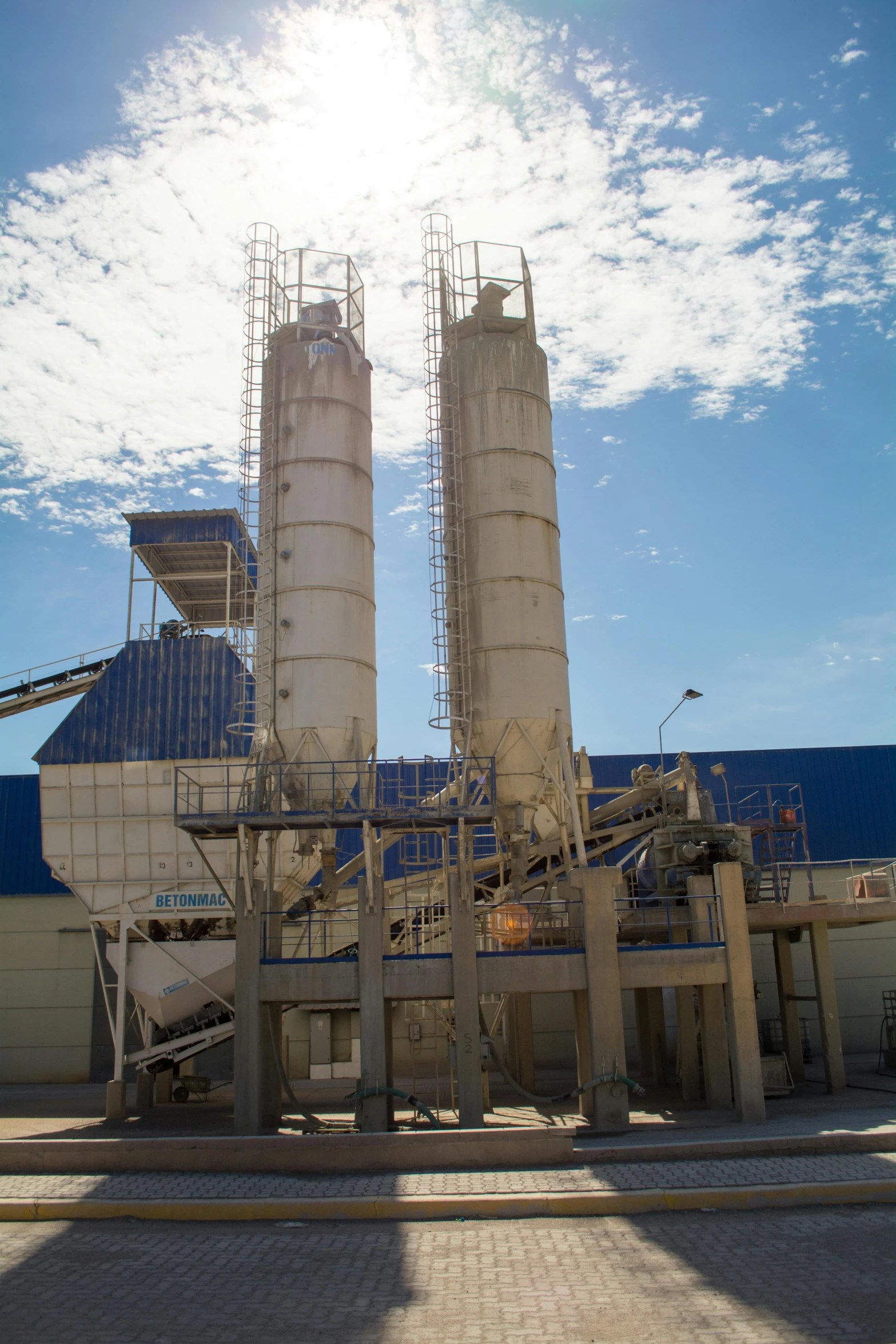 a large cement plant sitting on the side of a road, somalia, straight smooth vertical, complex machinery, blue