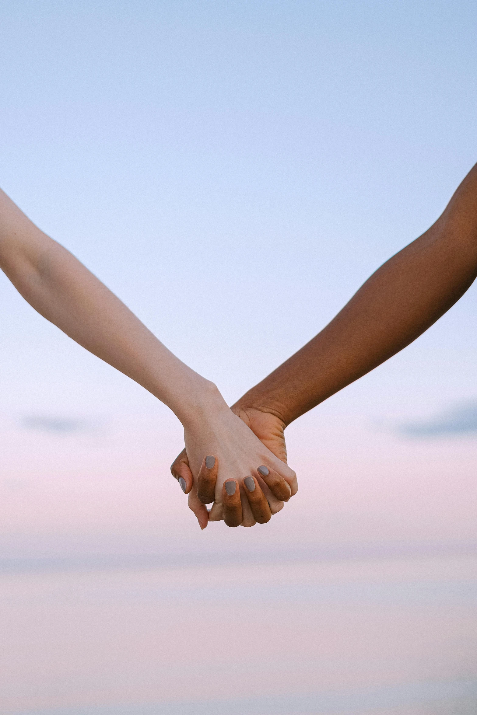a close up of two people holding hands, by Arabella Rankin, gradient brown to white, bright sky, varying ethnicities, during dawn