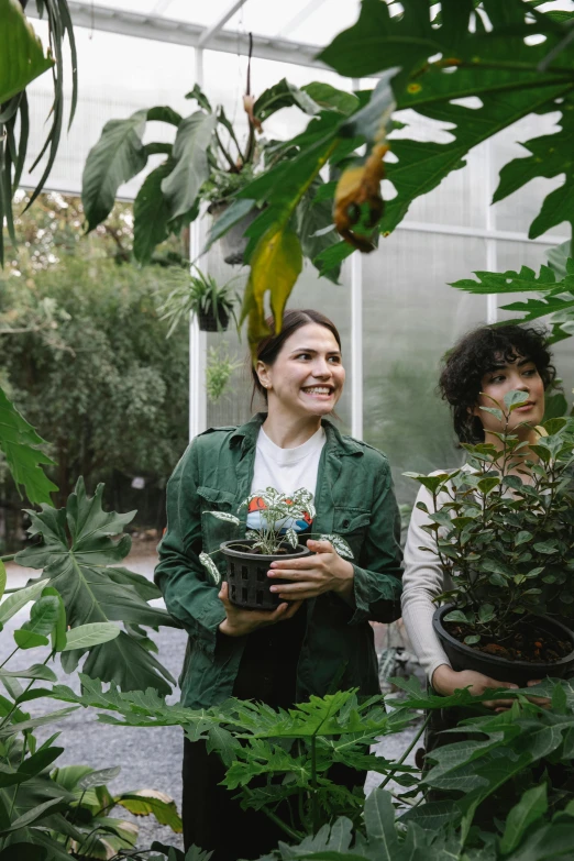 a couple of women standing next to each other in a greenhouse, tree and plants, hila klein, h3h3, show