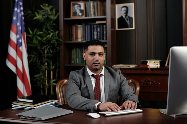 a man sitting at a desk in front of a computer, a portrait, by Ismail Acar, pexels contest winner, hurufiyya, dressed in a suit, official screenshot, khyzyl saleem, jovana rikalo