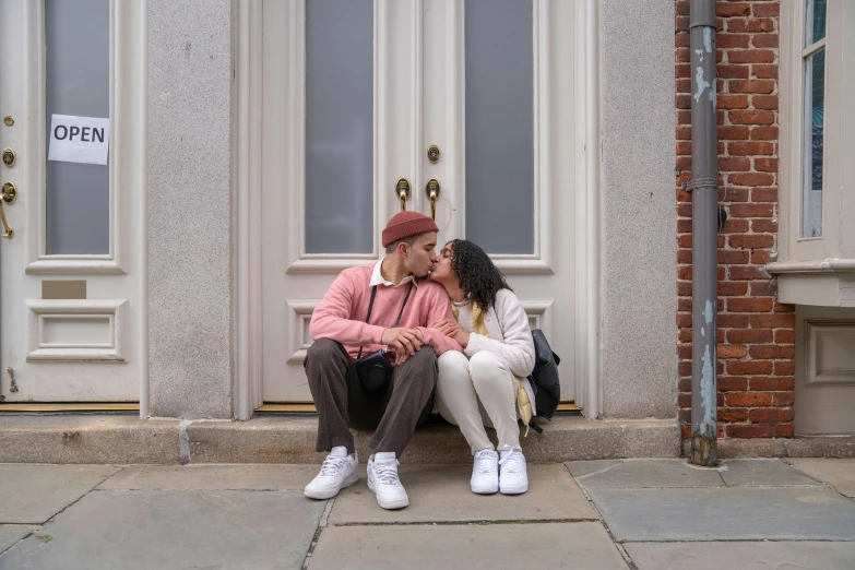 a man and woman sitting on the steps of a building, a photo, by Washington Allston, pexels contest winner, pink door, kissing, ashteroth, hispanic