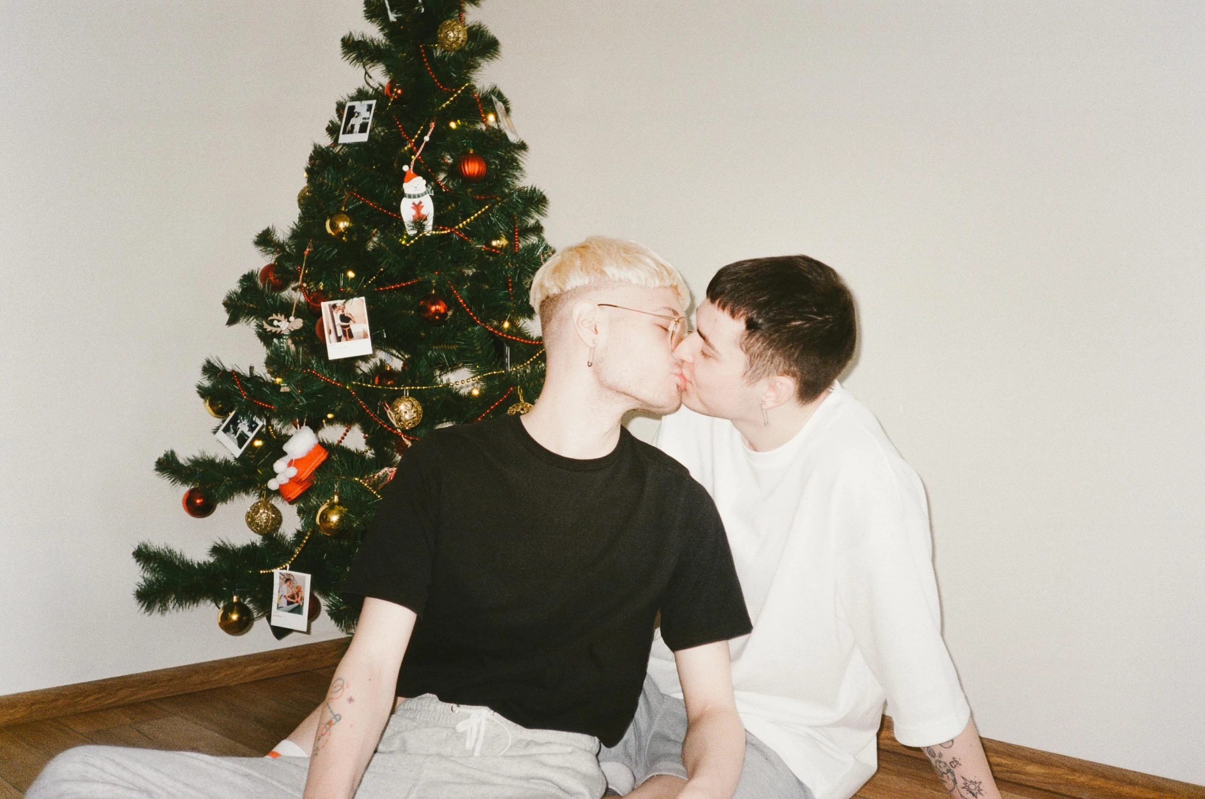 a couple of people sitting in front of a christmas tree, by Attila Meszlenyi, pexels, realism, nonbinary model, marton gyula kiss ( kimagu ), extremely pale, owen klatte