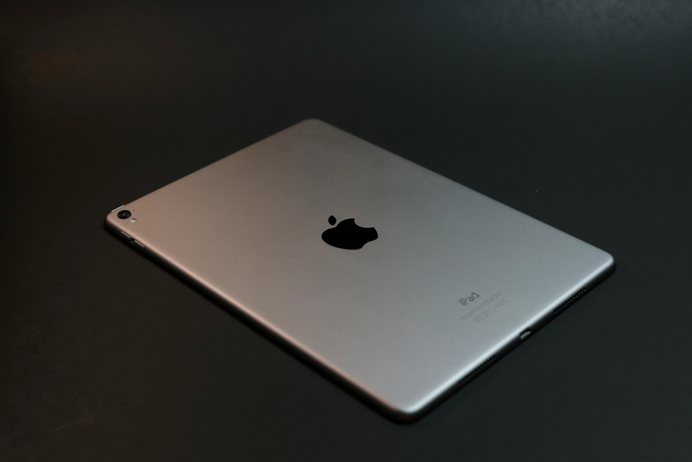 a silver ipad sitting on top of a table, by Carey Morris, unsplash, photorealism, on black background, back facing the camera, ilustration, apple