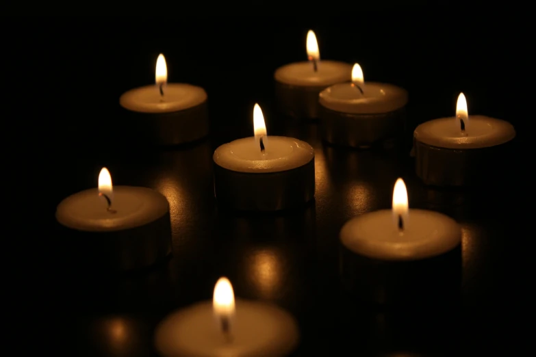 a group of lit candles sitting on top of a table, on a black background, ben watts, remembrance, floating candles