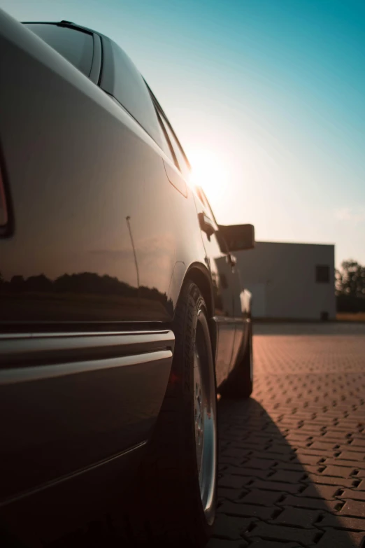 a black car parked on a brick road, pexels contest winner, photorealism, sunset lighting, profile perspective, automotive, shiny silver