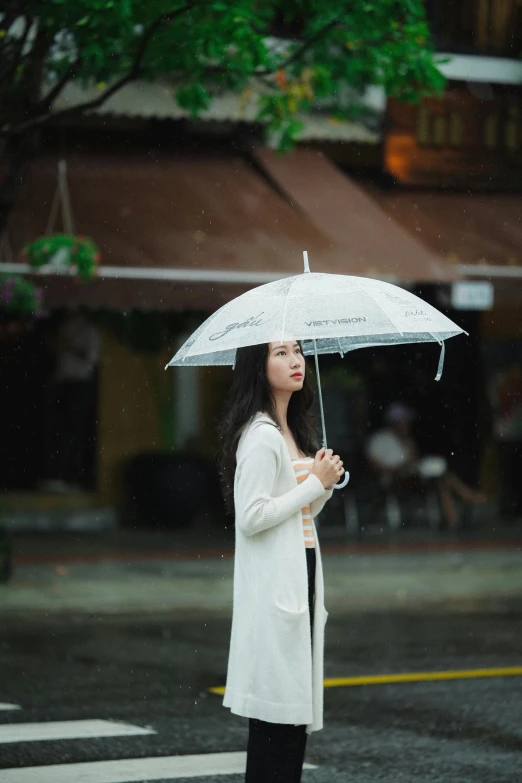 a woman standing in the rain holding an umbrella, by Tan Ting-pho, pexels contest winner, realism, wearing white clothes, handsome, gif, vietnamese woman
