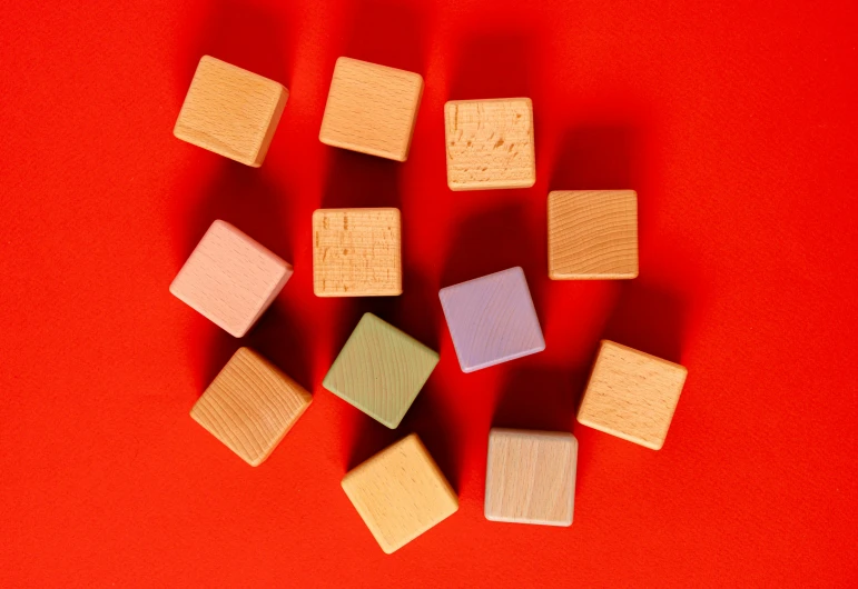 a group of wooden blocks sitting on top of a red surface, product image, square, orange pastel colors, 12