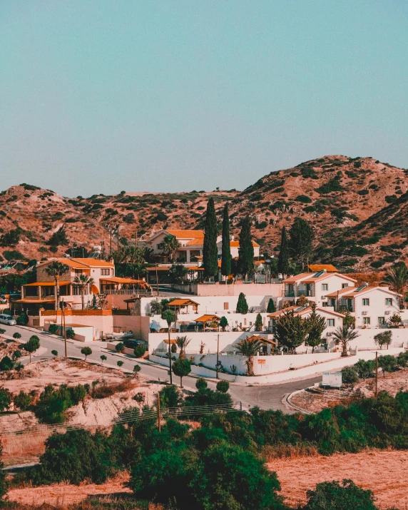 a small town with mountains in the background, a colorized photo, by Lucas Vorsterman, trending on unsplash, renaissance, cyprus, house on a hill, with palm trees in the back, flatlay