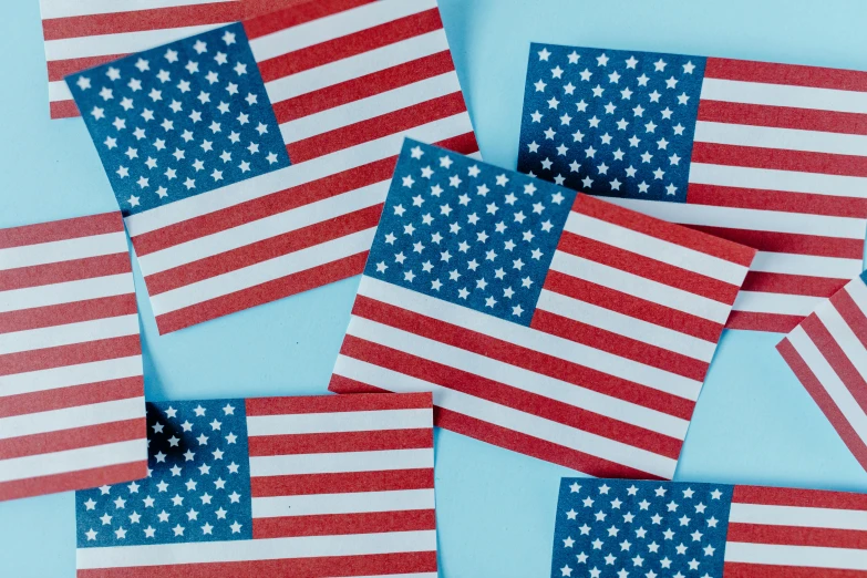 a bunch of american flags laying on top of each other, an album cover, by Carey Morris, pexels, with a blue background, cards, background image, cutout