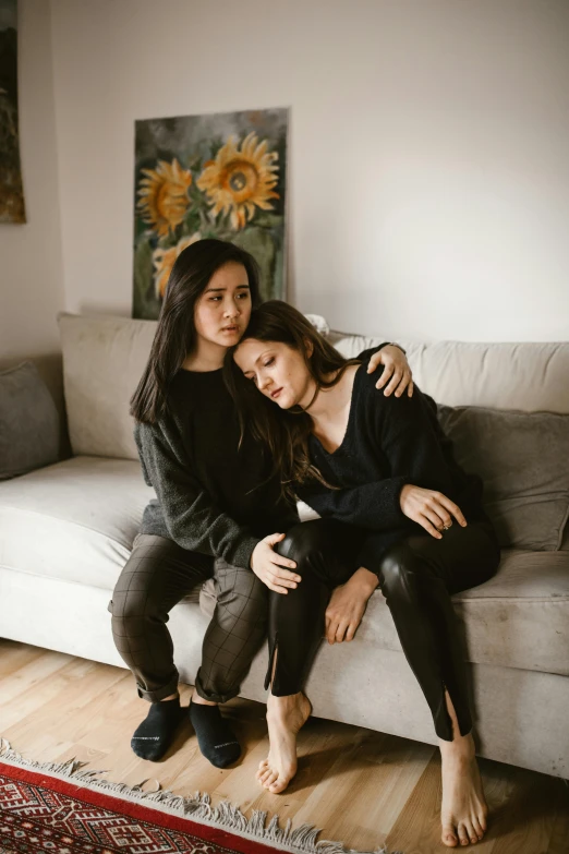 a couple of women sitting on top of a couch, a picture, trending on pexels, heartbreaking, mai anh tran, queer woman, daughter