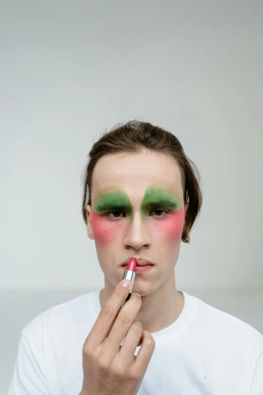 a man is putting makeup on his face, an album cover, inspired by Russell Dongjun Lu, trending on pexels, green face, caspar david, red cheeks, deity)