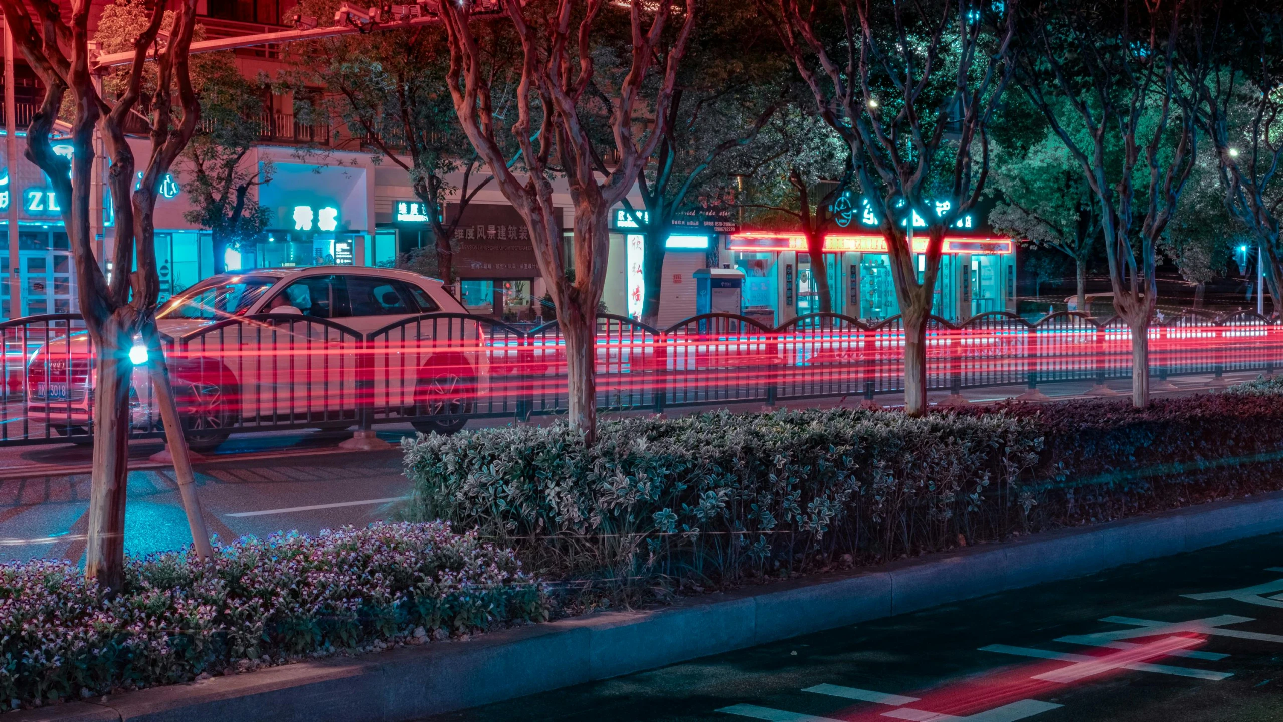 a car driving down a city street at night, by Daniel Lieske, pexels contest winner, baotou china, red and cyan, street corner, city lights made of lush trees