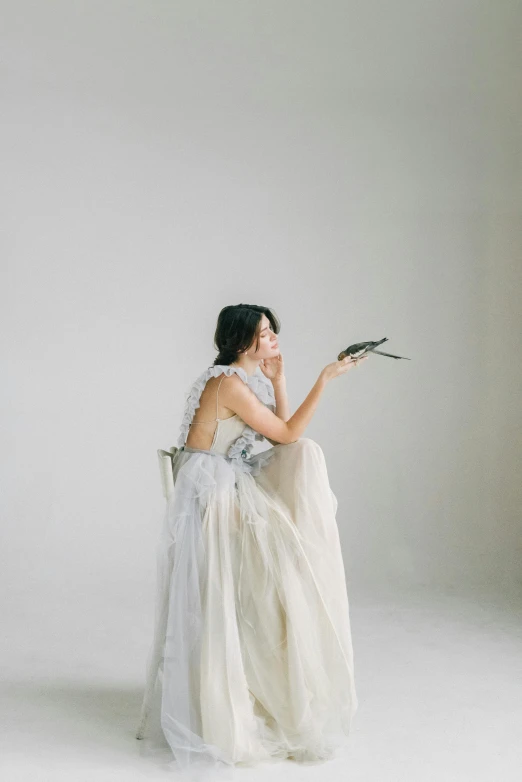 a woman sitting in a chair with a flower in her hand, unsplash, baroque, wearing a wedding dress, grey mist, yasumoto oka, ethereal macaw